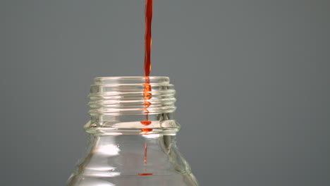 orange liquid pouring into glass bottle