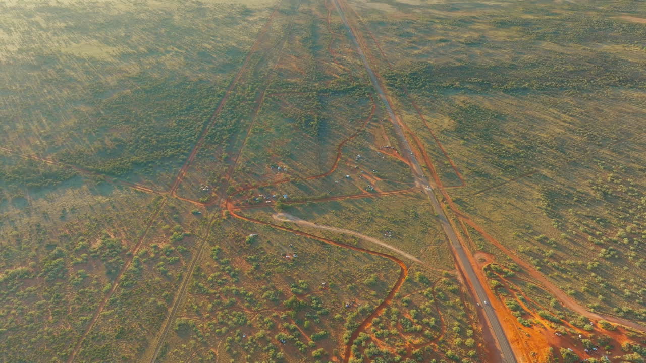 avión no tripulado sobrevolando la australia rural con pistas de carreras para la carrera del desierto de finke, alice springs 4k