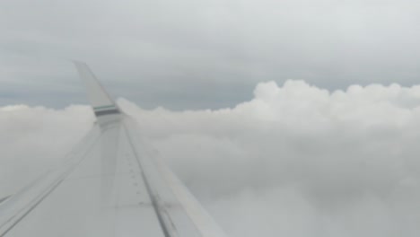 looking out the airplane over the wing as the plane gains altitude and passes through the clouds