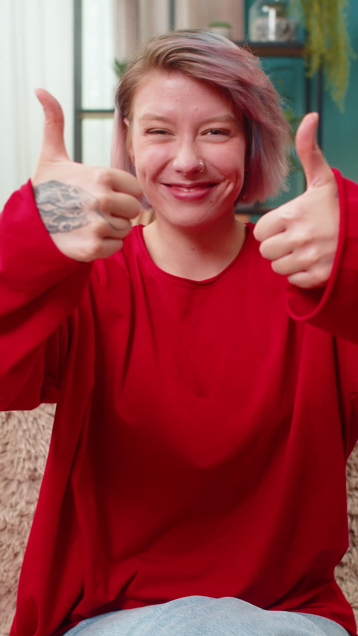 Young woman showing thumbs up gesture positive approval agreement good feedback smiling cheerfully
