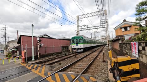 green train crossing a gated urban intersection.