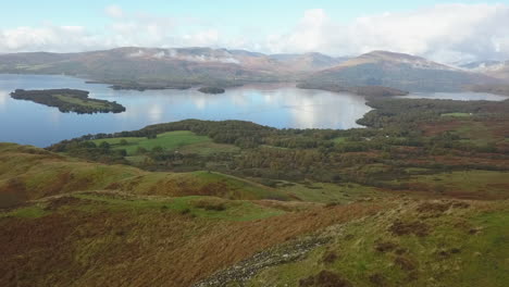 Aerial-flies-past-photographer-on-hill-top-overlooking-Scottish-loch