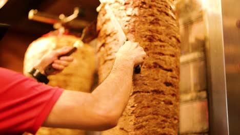 close-up of chef slicing kebab meat on vertical rotisserie grill