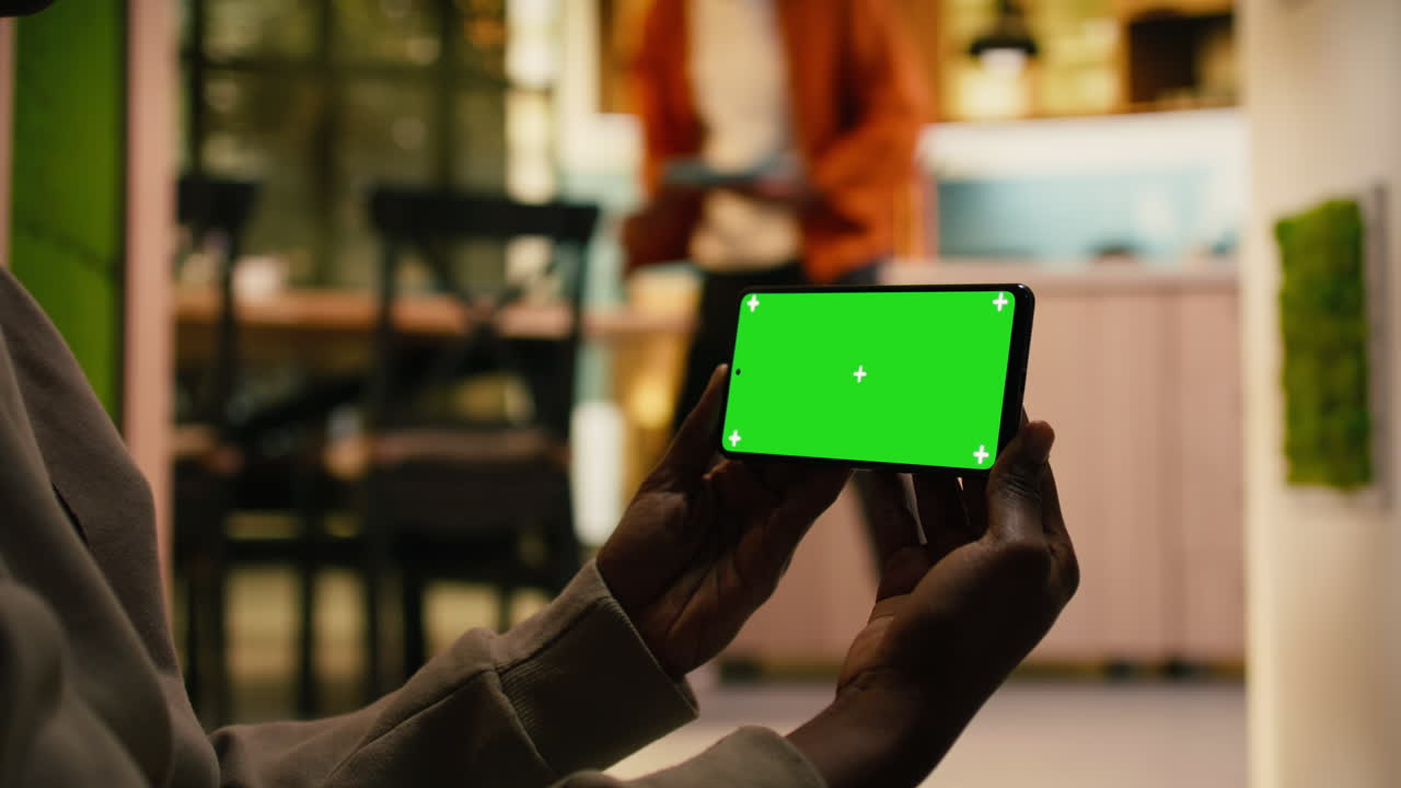 Schermo verde isolato su telefono cellulare accanto a una donna di colore che si rilassa.