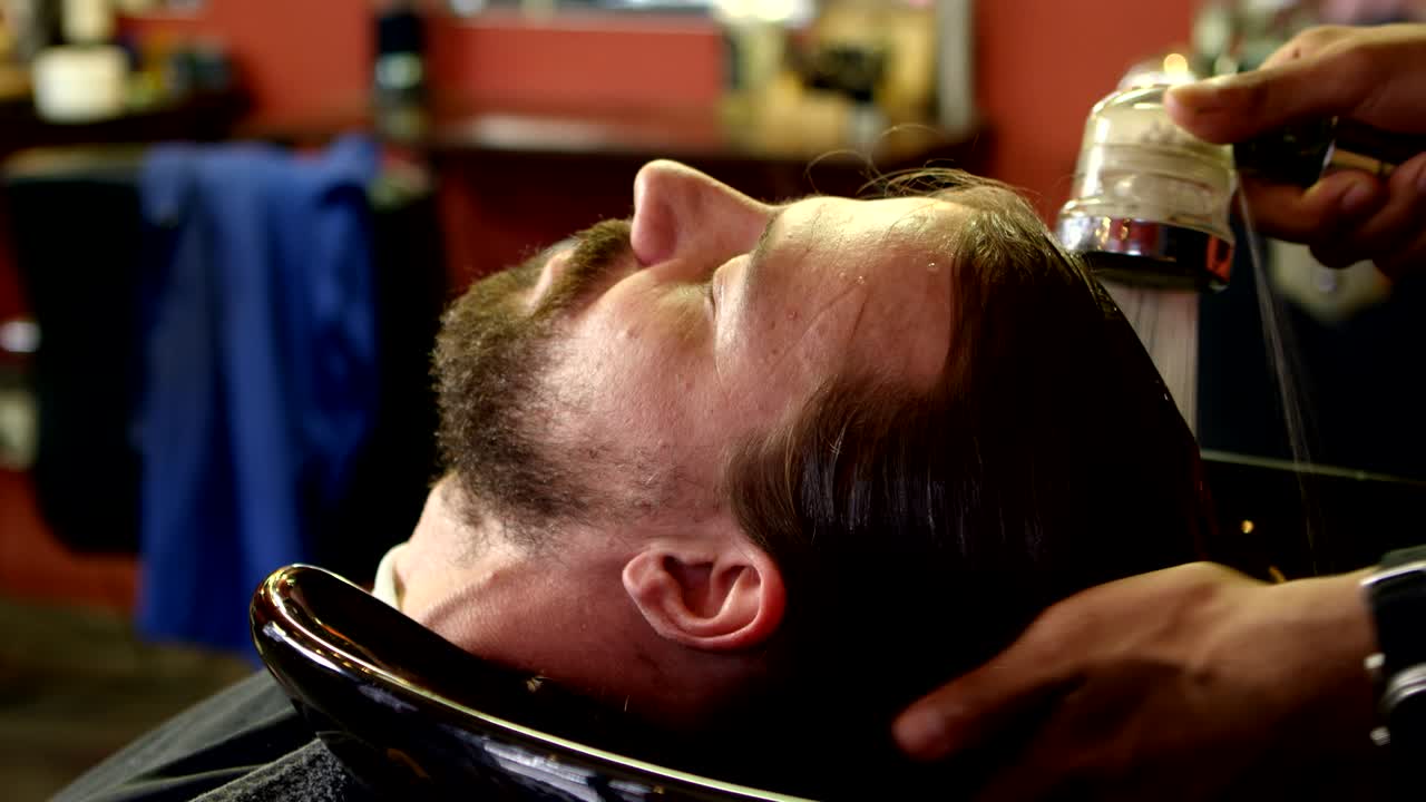 el hombre se está lavando el cabello.