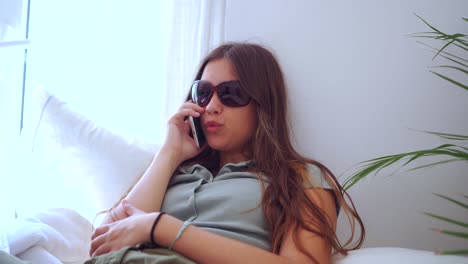 Woman-in-summer-outfit-browsing-on-mobile-phone-in-bedroom