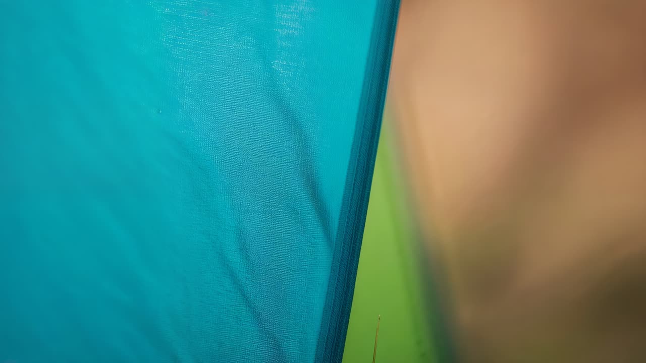 Shifting camera showing turquoise panel inside tent, revealing lime-green, tan panels and seam