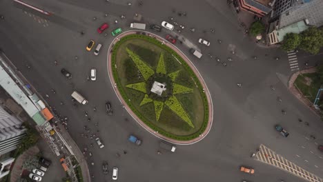 busy traffic roundabout hyperlapse or time lapse from top down aerial view with star shaped garden in its center during the day