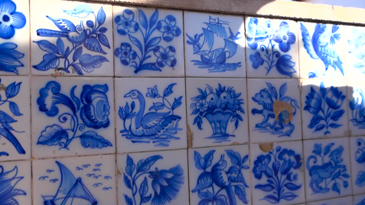Close up handheld footage of traditional Portuguese azulejos ceramic tiles in Lisbon with sunlight revealing worn painted details and patterns