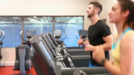 Pareja-Usando-Las-Cintas-De-Correr-En-El-Gimnasio