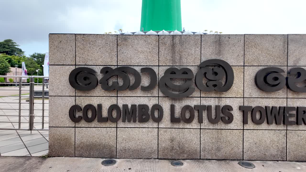 The colombo lotus tower sign displays sinhala and english script, a prominent landmark in sri lanka's capital city. panning shot
