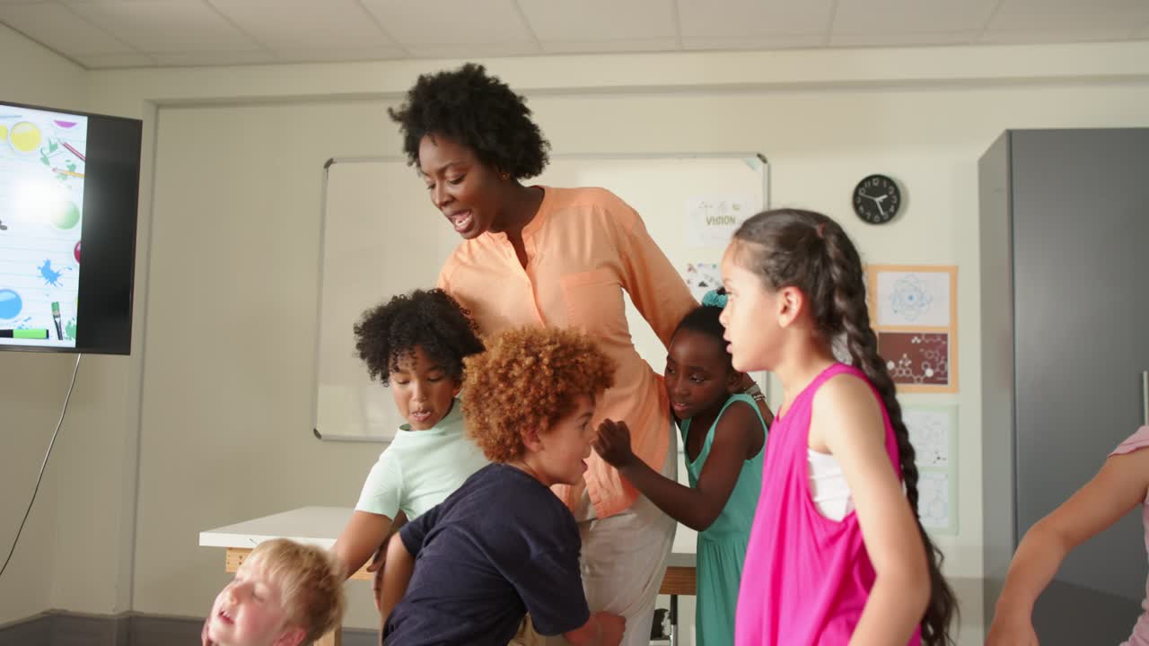 Insegnante afroamericana con sei bambini che si abbracciano davanti a una lavagna bianca, con i bambini che cercano conforto.
