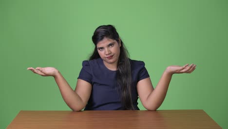 young overweight beautiful indian businesswoman against green background