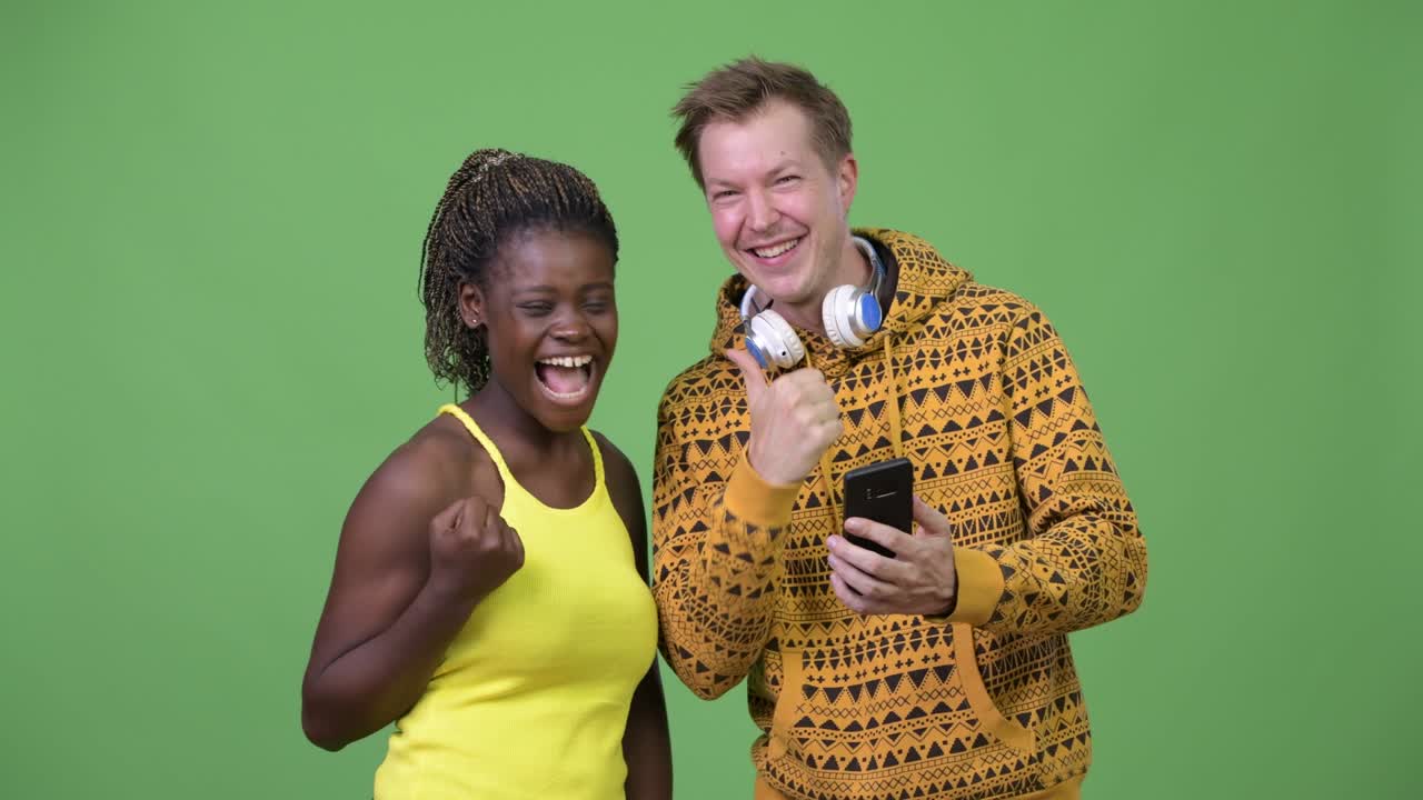 una joven pareja multiétnica usando el teléfono juntos.