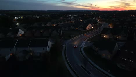 Car-driving-through-residential-modern-American-neighborhood-at-night