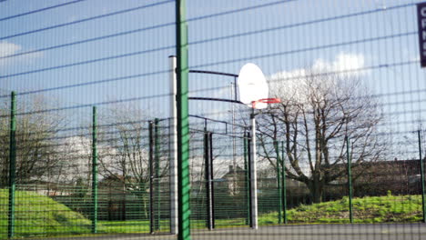 Basketball-hoop-through-fence-with-fast-freeway-cars-in-background