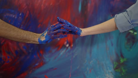 pareja de manos en pinturas en el frente lienzo colorido, movimiento tocante