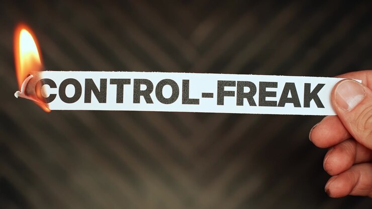 Burning “control-freak” label held by hand, symbolizing trust, flexibility, emotional growth, and letting go of rigid control, micromanagement, and fear-based behavior.