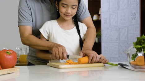 Father-and-daughter-cutting-carrot.