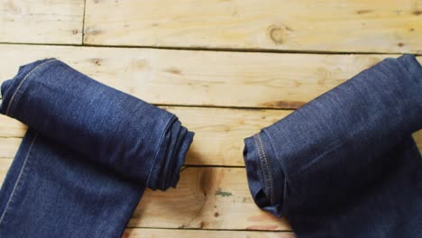 video of two pairs of rolled up denim trousers with with copy space on wooden background