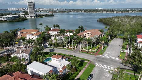 luxury homes and villas of st. armands key in sarasota, florida. sunny day with clouds at sky. aerial orbit wide shot. green islands and towers in distance. junction in rich quiet suburbia.