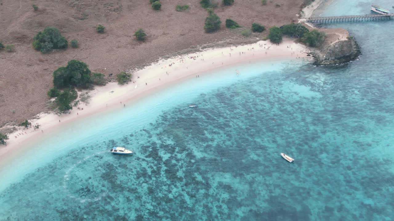Drone shot of beautiful beach with blue clear blue water, pink beach and boats in Asia