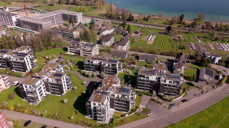 Lake Zurich with luxury penthouse apartment houses with solar panels on roof. Sunny day in swiss district with lake view. Aerial tilt down shot. Wädenswil, Switzerland.