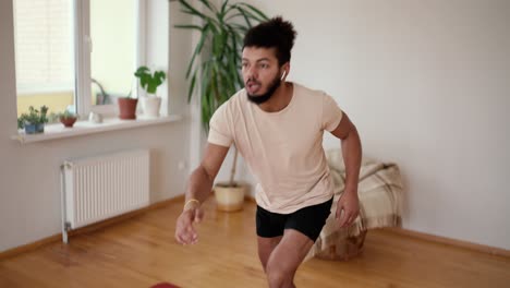 Athletic-fit-man-doing-forward-lunge-exercises-at-home-with-minimalist-interior