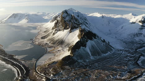 aerial tilt shot overlooking a snowy mountain range, winter golden hour in south iceland