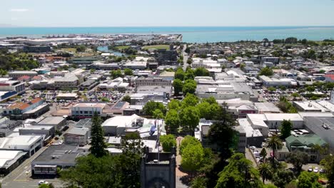 Aerial-of-Trafalgar-Street-Promenade-in-Nelson-city,-reveal-of-Christ-Church-Cathedral-and-waving-New-Zealand-flag