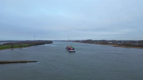 Luftaufnahme-Eines-Frachtcontainerschiffs,-Das-Sich-An-Einem-Bewölkten-Tag-Entlang-Der-Beneden-Merwede-Nähert