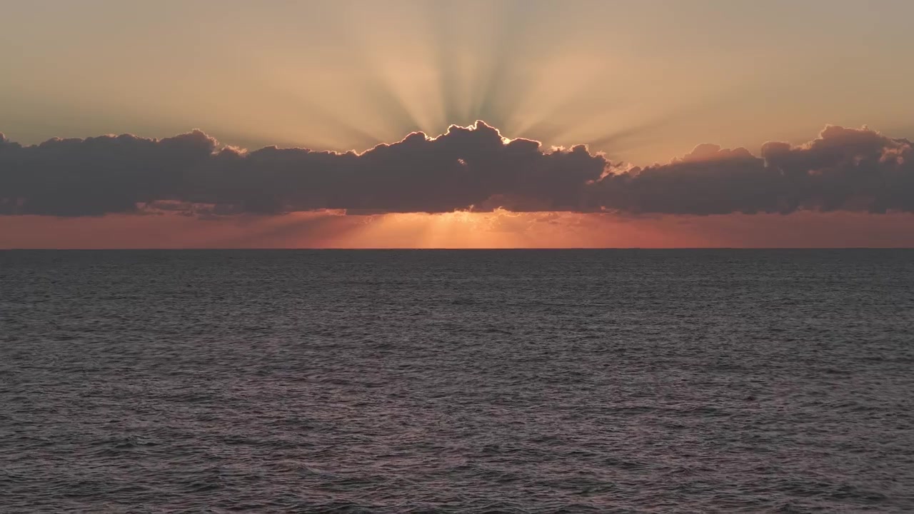 Cinematic Sunrise Over The Ocean In Queensland, Australia, With Crepuscular Rays Breaking Through Dark Cloud Bank. wide drone shot