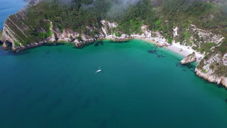 hidden turquoise cove on virgin island beach with surrounding cliffs and anchored sailboats, crozon peninsula, brittany, france