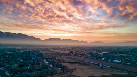 Glorious-sunrise-over-a-city-in-the-valley-with-morning-rush-hour-traffic-and-hazy-smog---aerial-hyperlapse