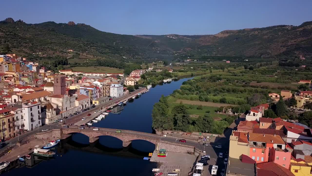 Drone aerial shot of the colourful town of Bosa in Sardinia.Bank turn right over the river temo with awesome green landscape. The Malaspina castle is dominating above the village