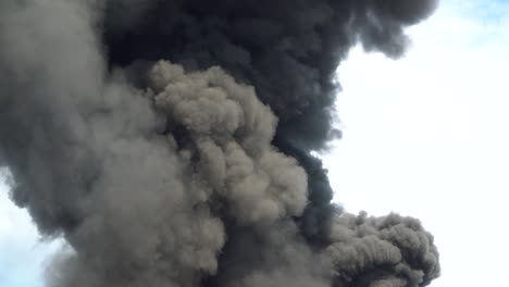 black smoke rises into the sky. a big chemical fire at a factory building. thick black smoke covers the sky.