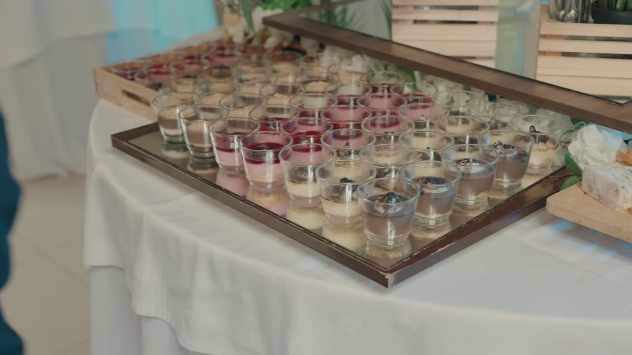 Rækker af farverige dessertshots, der er pænt udstillet på et spejlbelagt buffetfad