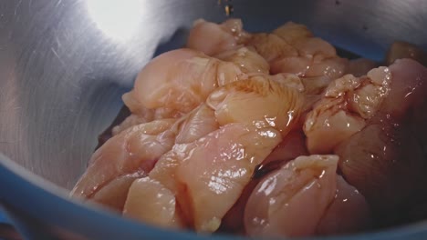 condimentar pollo crudo fresco picado en un bol y mezclarlo todo con una cuchara de madera, vista de cerca