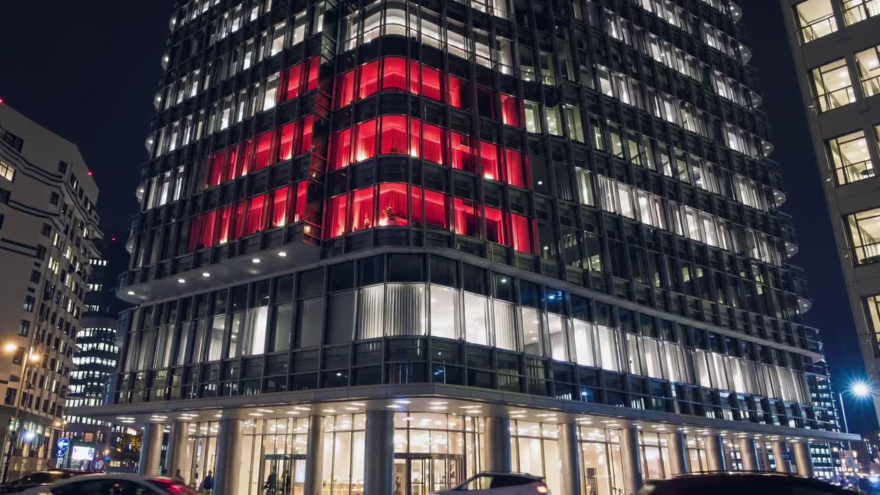 빛나는 은 십자가는 현대 유리 건물 전면을 비추고, 어두운 도시 야간 풍경에 대해 눈에 띄는 빛을 내며, 희망과 인도주의적 지원을 상징합니다.