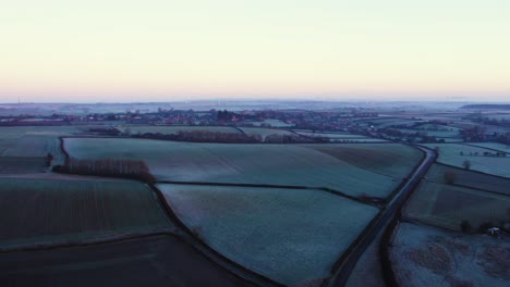 a road leading towards an english countryside village on a cold frosty winters morning