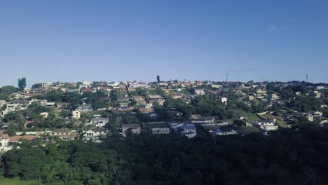 Drone-flying-over-residential-homes-moving-towards-the-ocean-on-a-clear-blue-day-with-good-visibility