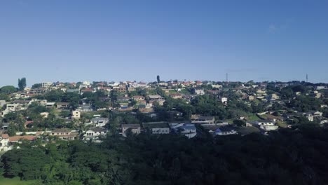 drone volando sobre casas residenciales moviéndose hacia el océano en un día azul despejado con buena visibilidad