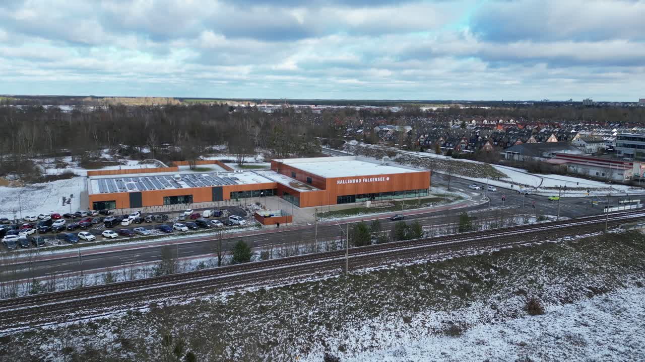 Indoor swimming pool with solar panels surrounded by snow and suburban homes in Falkensee Germany. Spectacular aerial view flight panorama overview drone