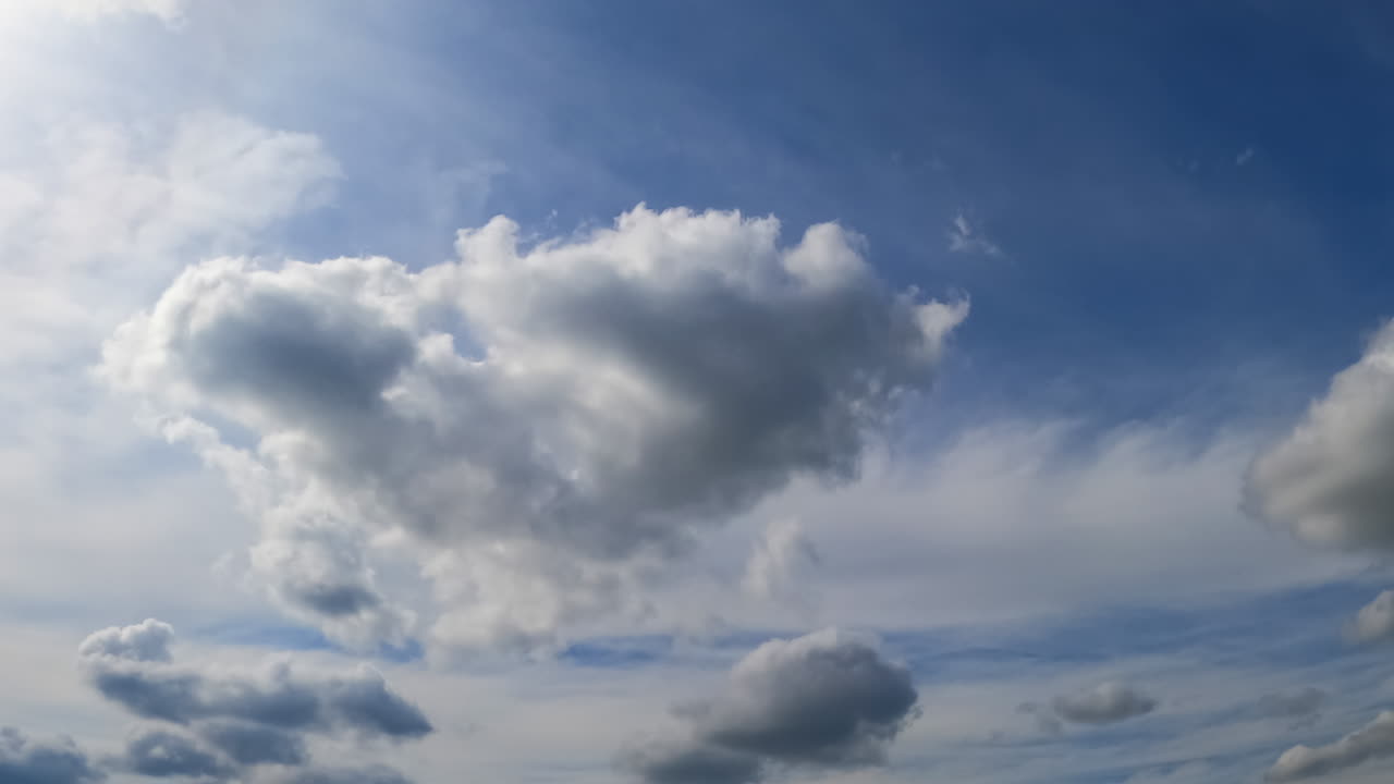 Clouds transform in the atmosphere. Little white clouds grow into a dramatic cloudscape. Low angle view. Timelapse.