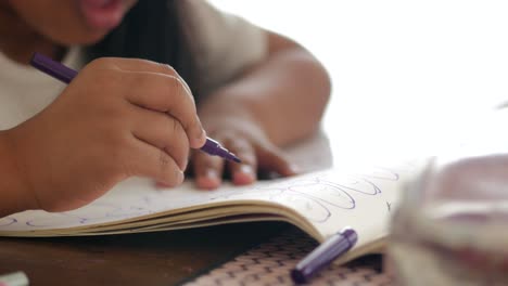 child drawing with a purple marker in a notebook