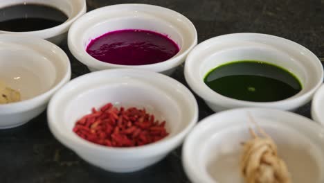 colorful sauces and spices in white bowls on table, pan right