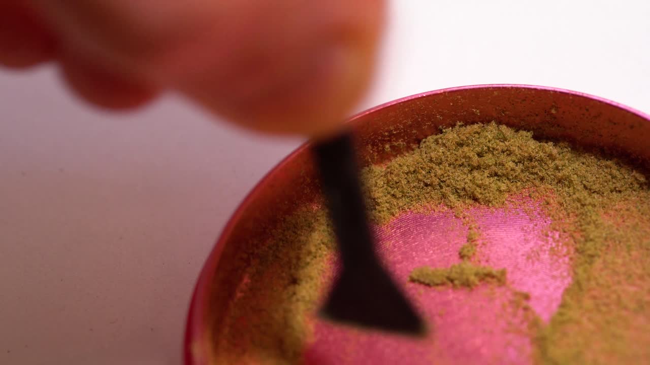 Scraping keef from the bottom of marijuana grinder