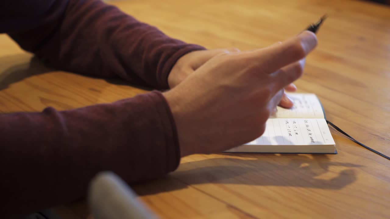Side shot of man writing in a notebook then closing the notebook