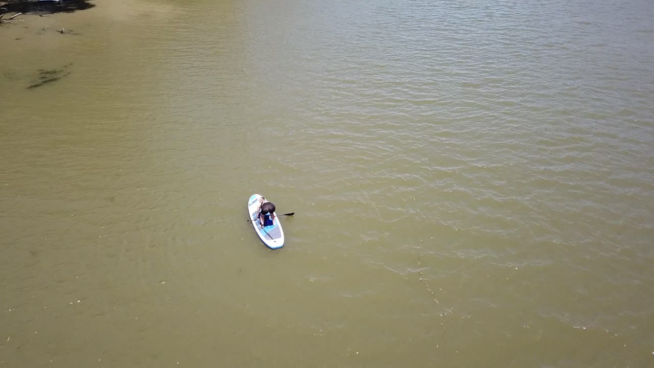 패들 보드에 일어서려고 노력하는 강 위의 드론 공중