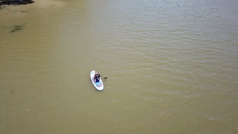 Drohnenantenne-über-Dem-Fluss-Frau,-Die-Versucht,-Auf-Dem-Paddelbrett-Aufzustehen